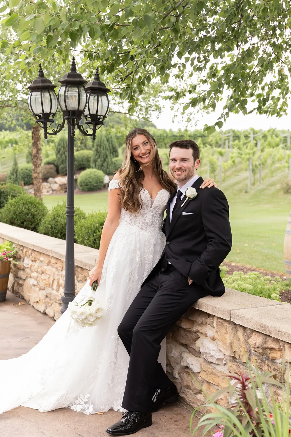Couple on a stone wall beside the lamp posts at Folino Estate