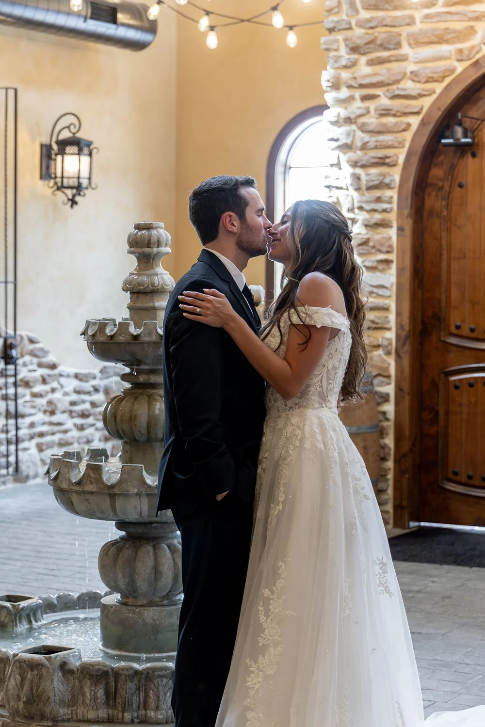 Couple kissing beside a stone fountain at Folino Estate