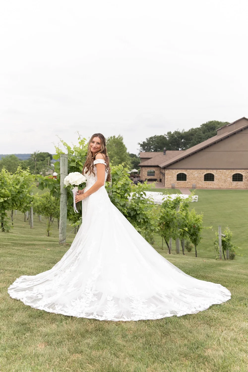 Bride in the vineyard with her train spread across the grass
