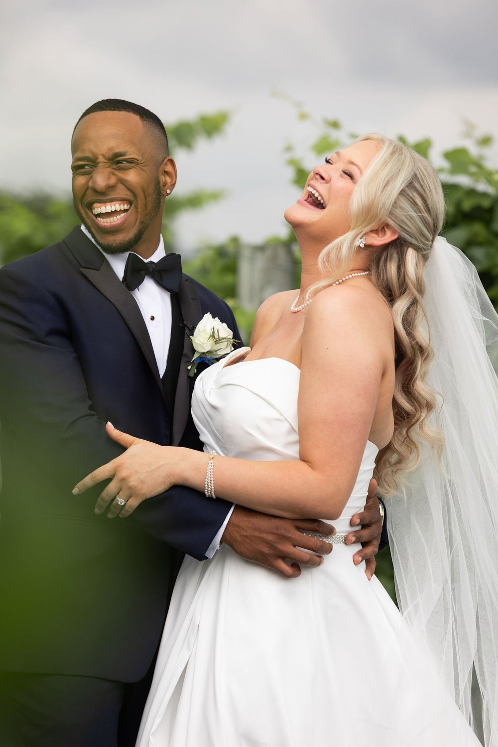Bride and groom laughing together in the vineyard