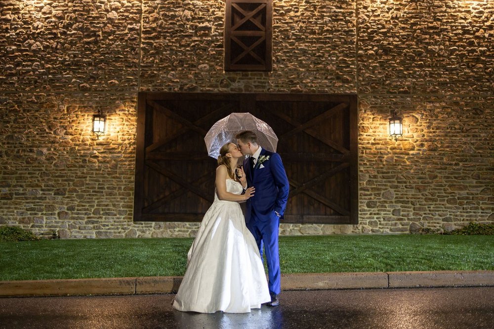 Couple under a clear umbrella against the stone wall at night