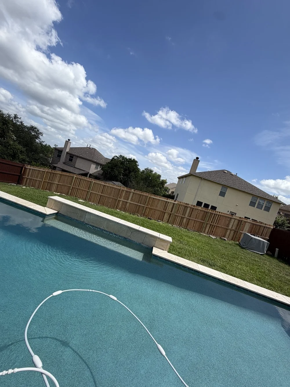 Backyard view of the completed Stone Oak cedar fence beside the swimming pool