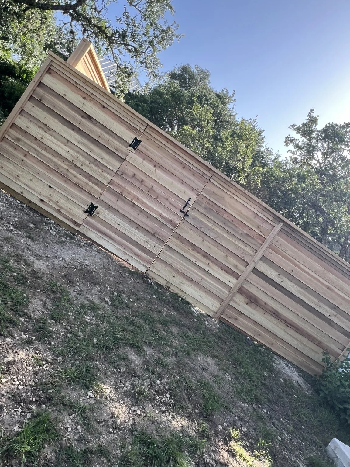 Matching horizontal cedar pedestrian gate with black hinges and latch