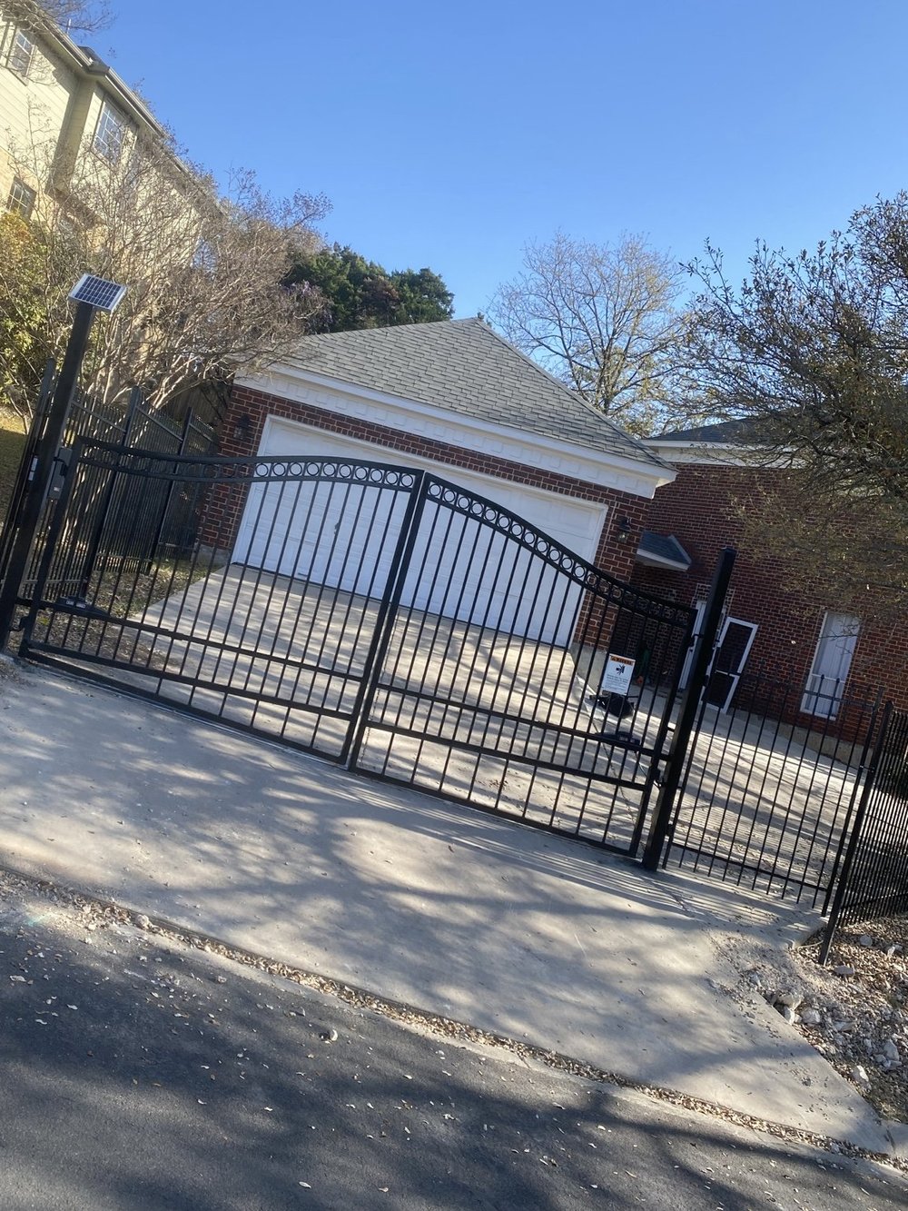 Leon Springs automatic double gates and adjoining wrought iron fence with solar panel