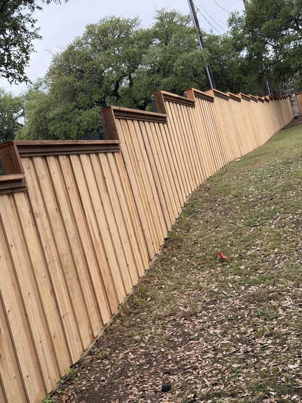 Stepped six-foot board-on-board wood fence with top cap and trim in Boerne