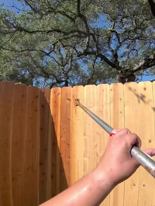 Pressure-washing the existing wood fence during the Shavano Park fence-staining project