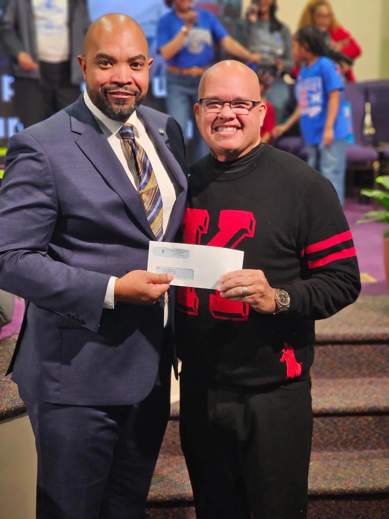 Allen University’s Vice President for Institutional Advancement receiving a gift from a church leader