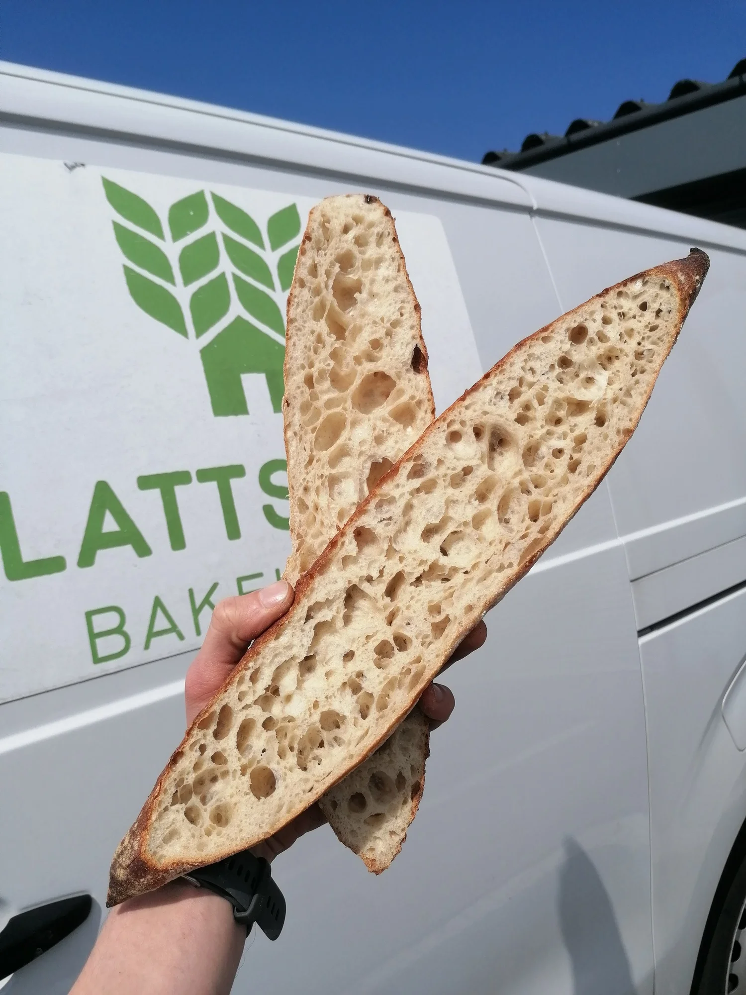 A split baguette held up against the Plattsville van