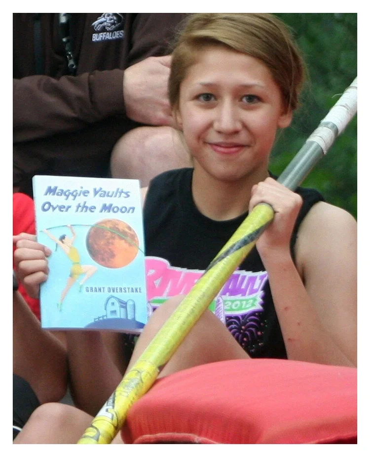 Pole vault athlete holding her Maggie Award book after a meet