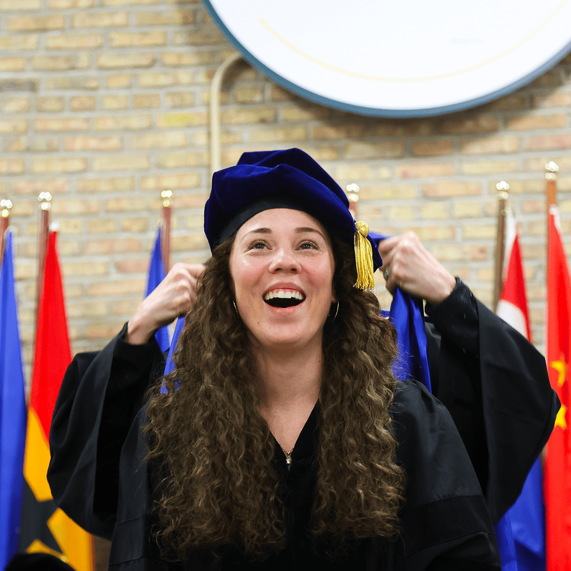 An ICSW graduate in cap and gown celebrating at commencement
