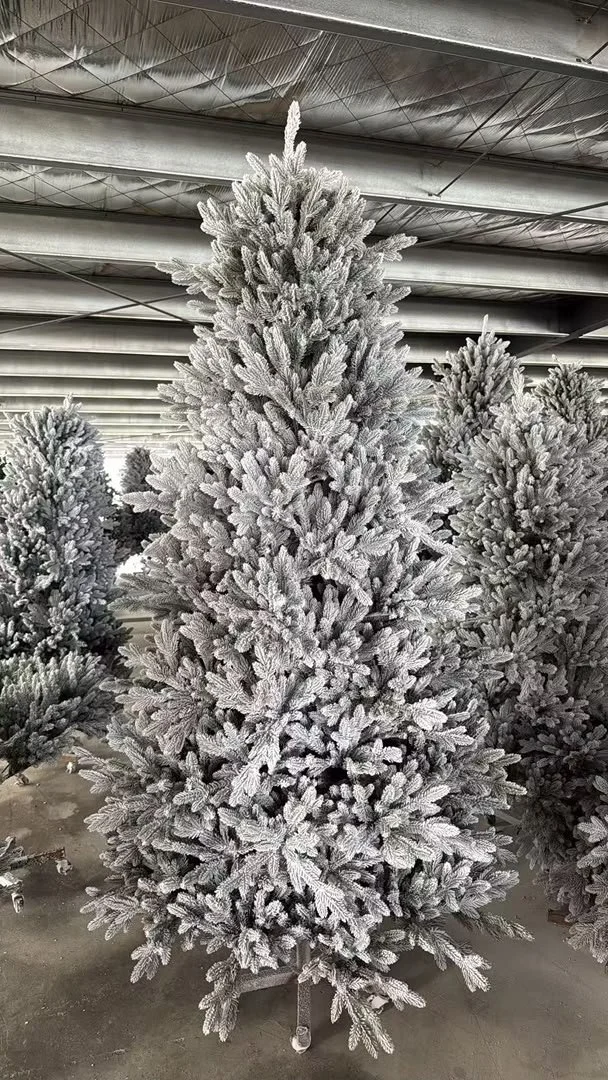 A snow-flocked artificial tree standing in a manufacturing facility