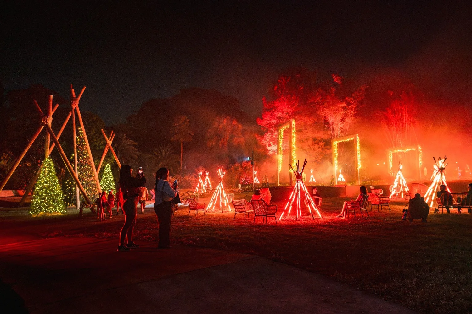 Guests gathering among warm red LED fires, timber structures and Christmas trees during Winter Solstice in 2025