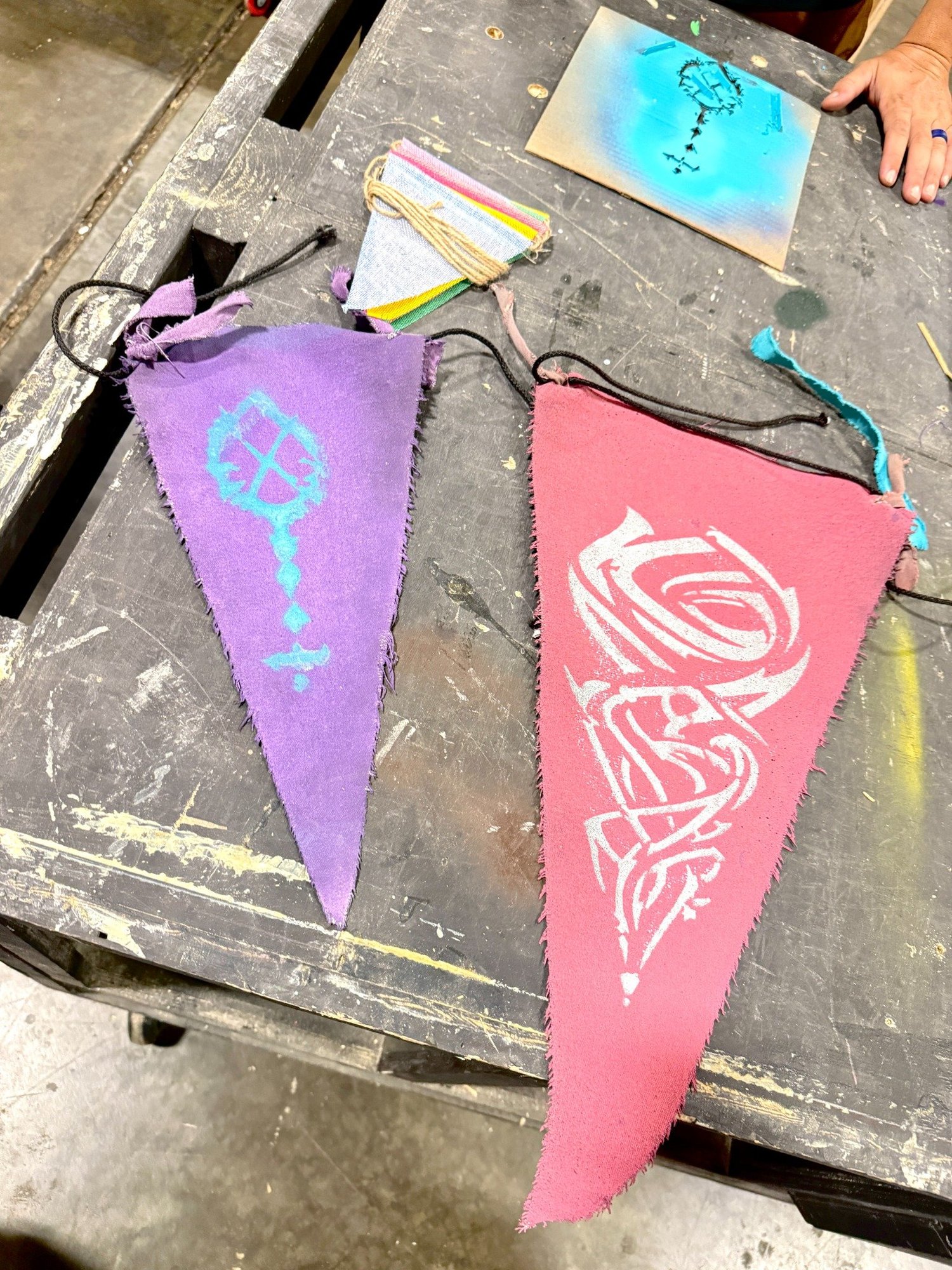 Hand-dyed and stenciled Driftlands flags on a workshop table