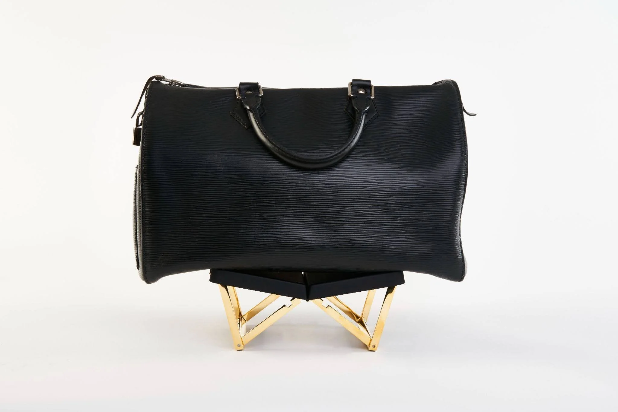 Black leather handbag resting on a folding BAGCEIT® purse stand 