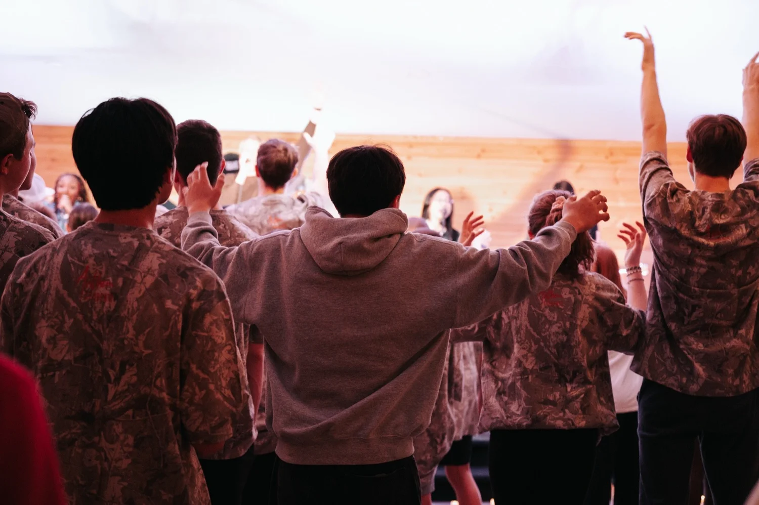 Students worshiping with hands raised at a camp with Anthem Students