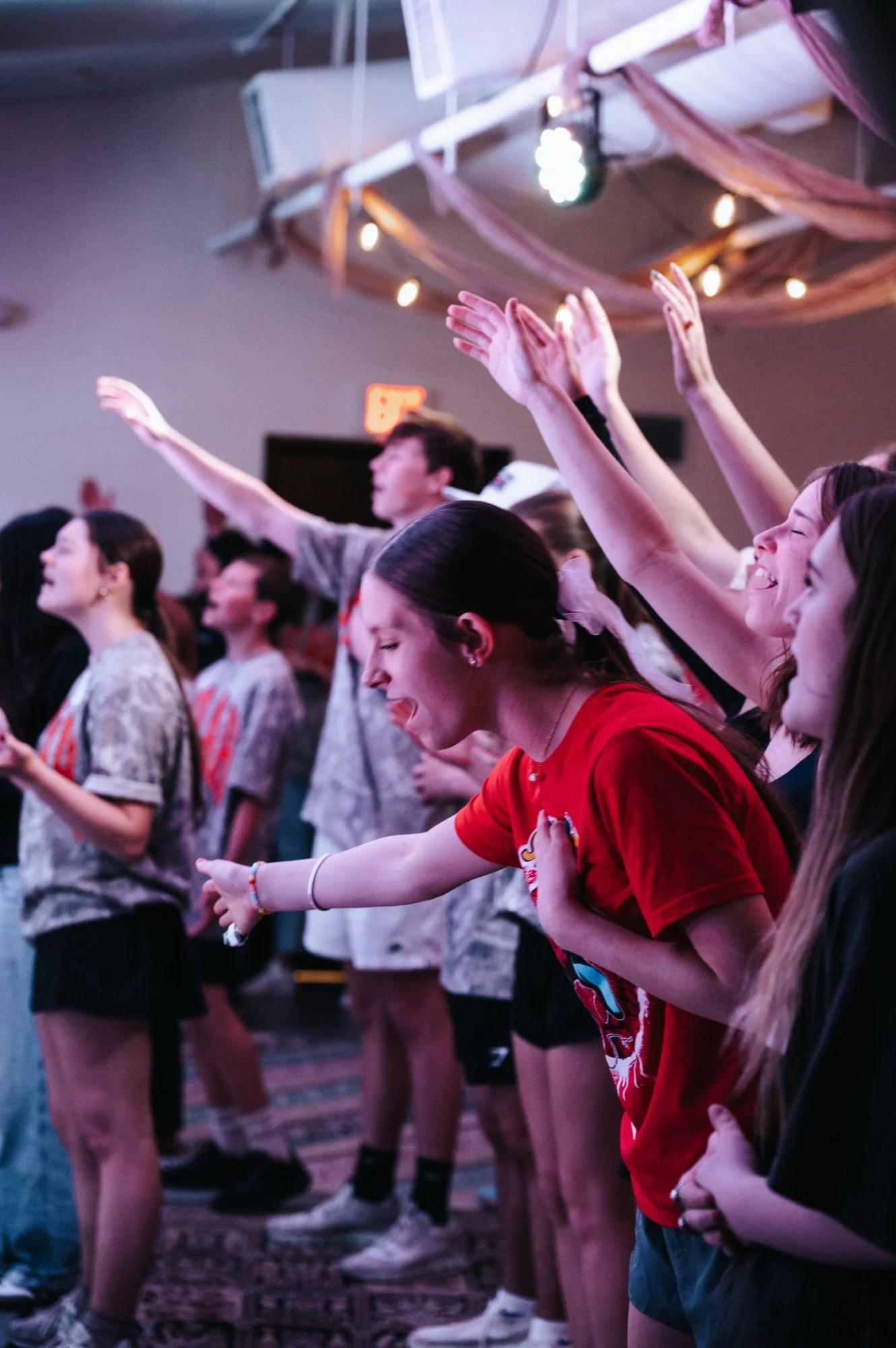 Students worshiping with hands raised at Anthem Students