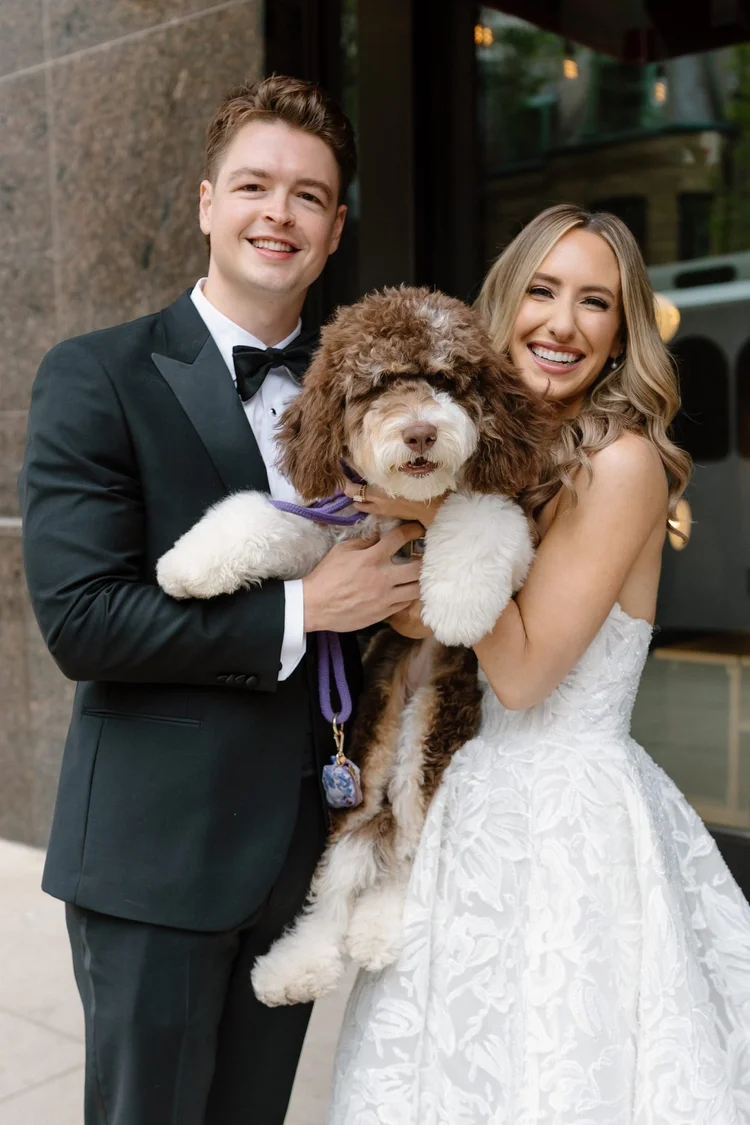 Bride and groom smile as they hold Macaroni, their brown and white Australian Mountain Doodle, on their Chicago wedding day.