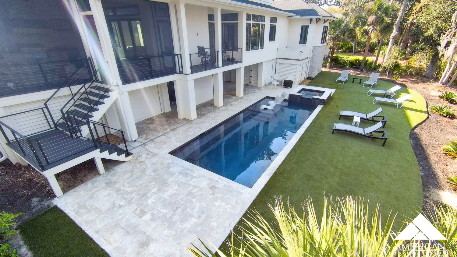 Travertine pool deck with spa and artificial turf at a Savannah-area home, installed by American Paving Design