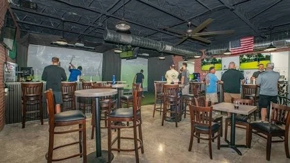 Golfers practicing on simulator bays at The Par Pub