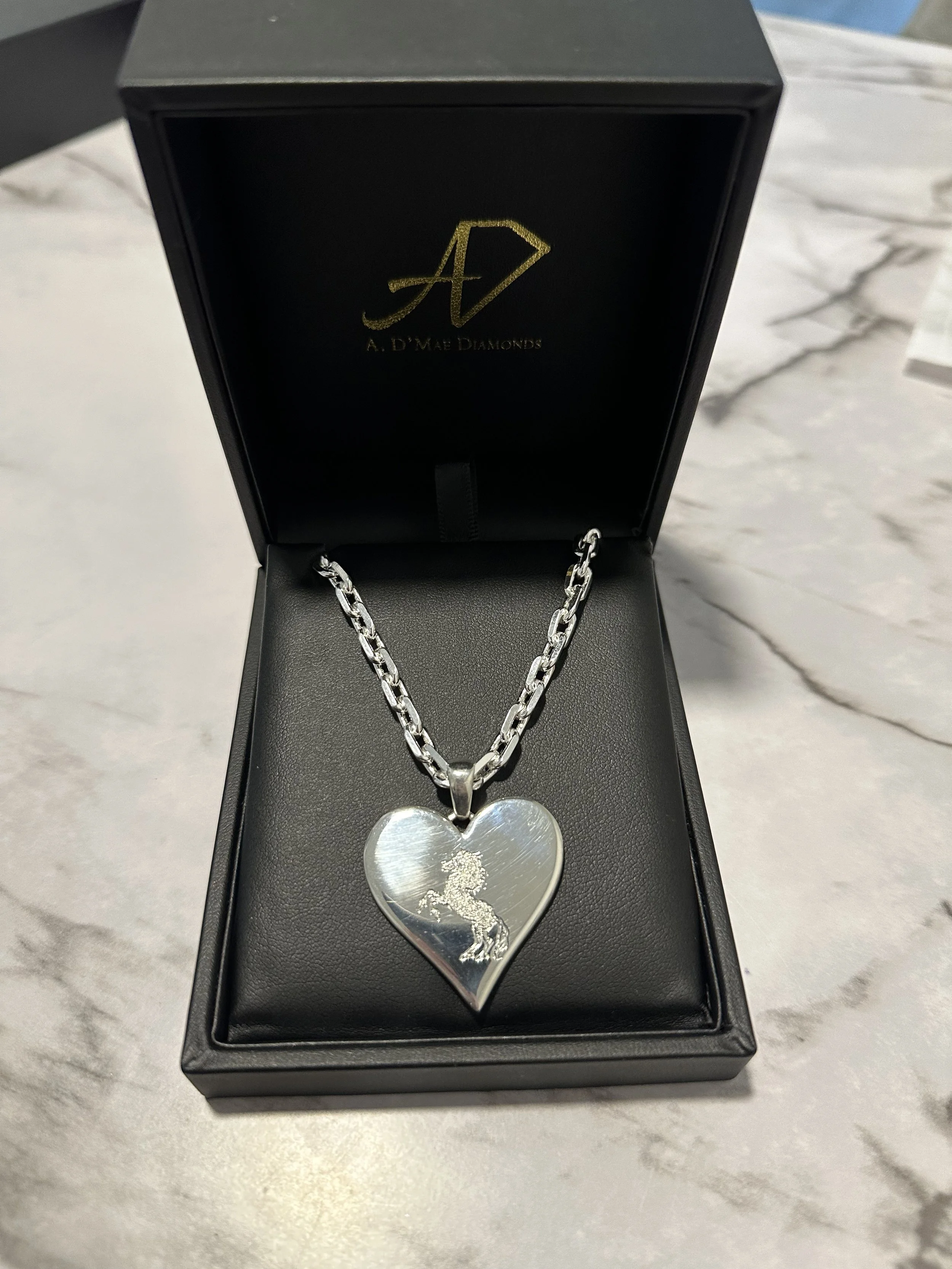 Custom three-dimensional heart necklace with band logo engraving in A. D'Mae Diamonds presentation box, Los Angeles