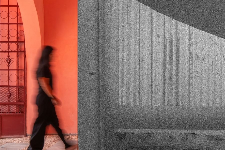 Interior de Casa Rosa: una persona cruza un arco pintado de rojo junto a una escalera curva.