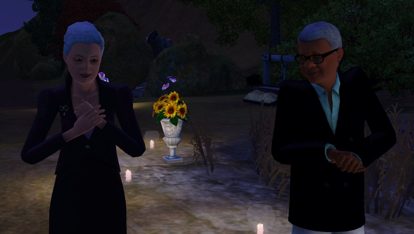 Bridget and Altman Tevellyn smiling and clapping. Bridget wears a dark purple blazer and modest skirt. Altman wears a navy blue double-breasted blazer, a cyan dress shirt, and off-white trousers.