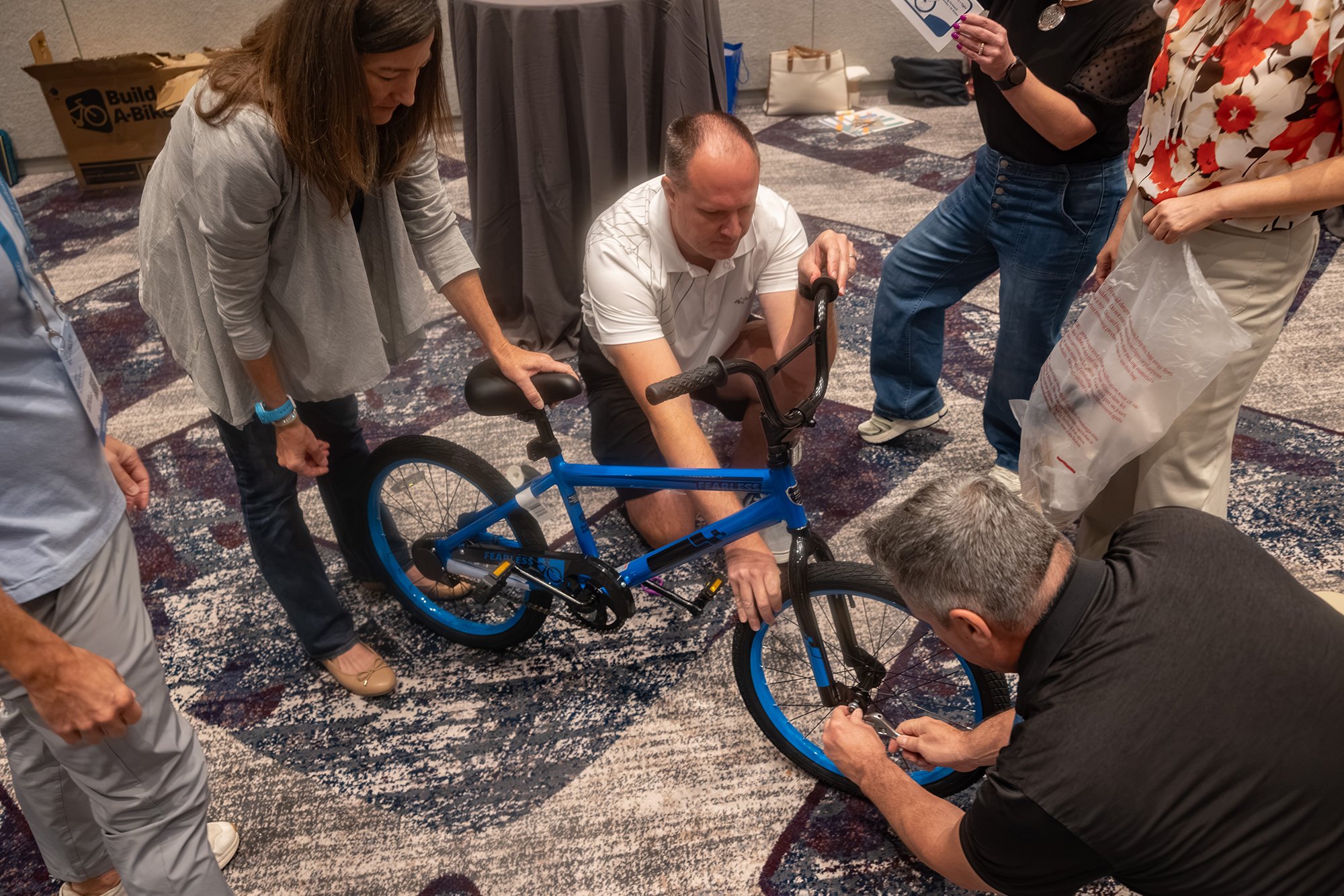 Participants work together to assemble a blue bicycle.