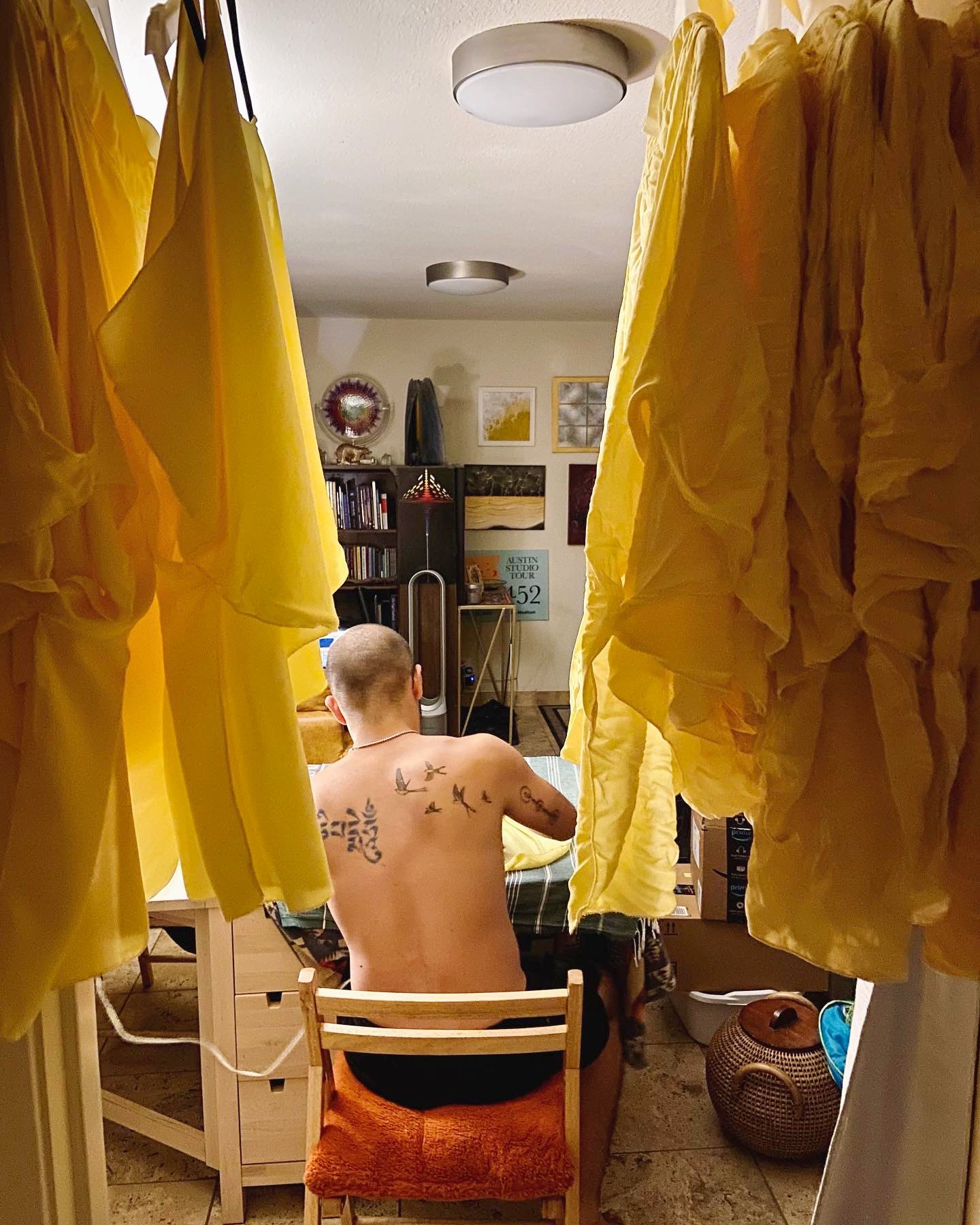 Navaji David Nava constructing KOMOREBI costumes in his studio with Astral Study II and Sea of Lightning visible behind him