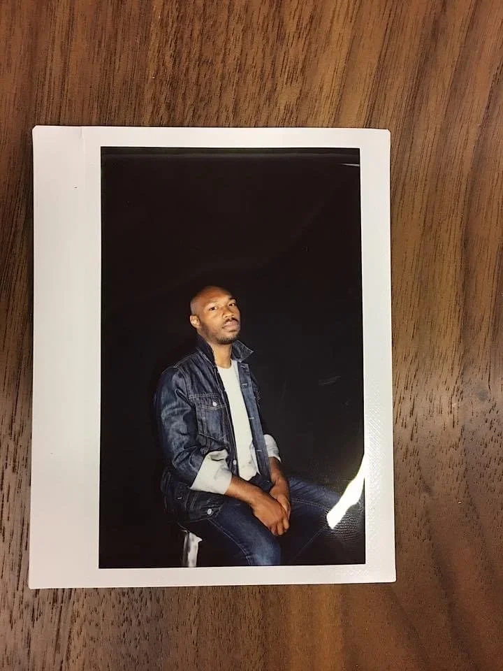 Printed studio portrait of CJ Johnson resting on a wooden table