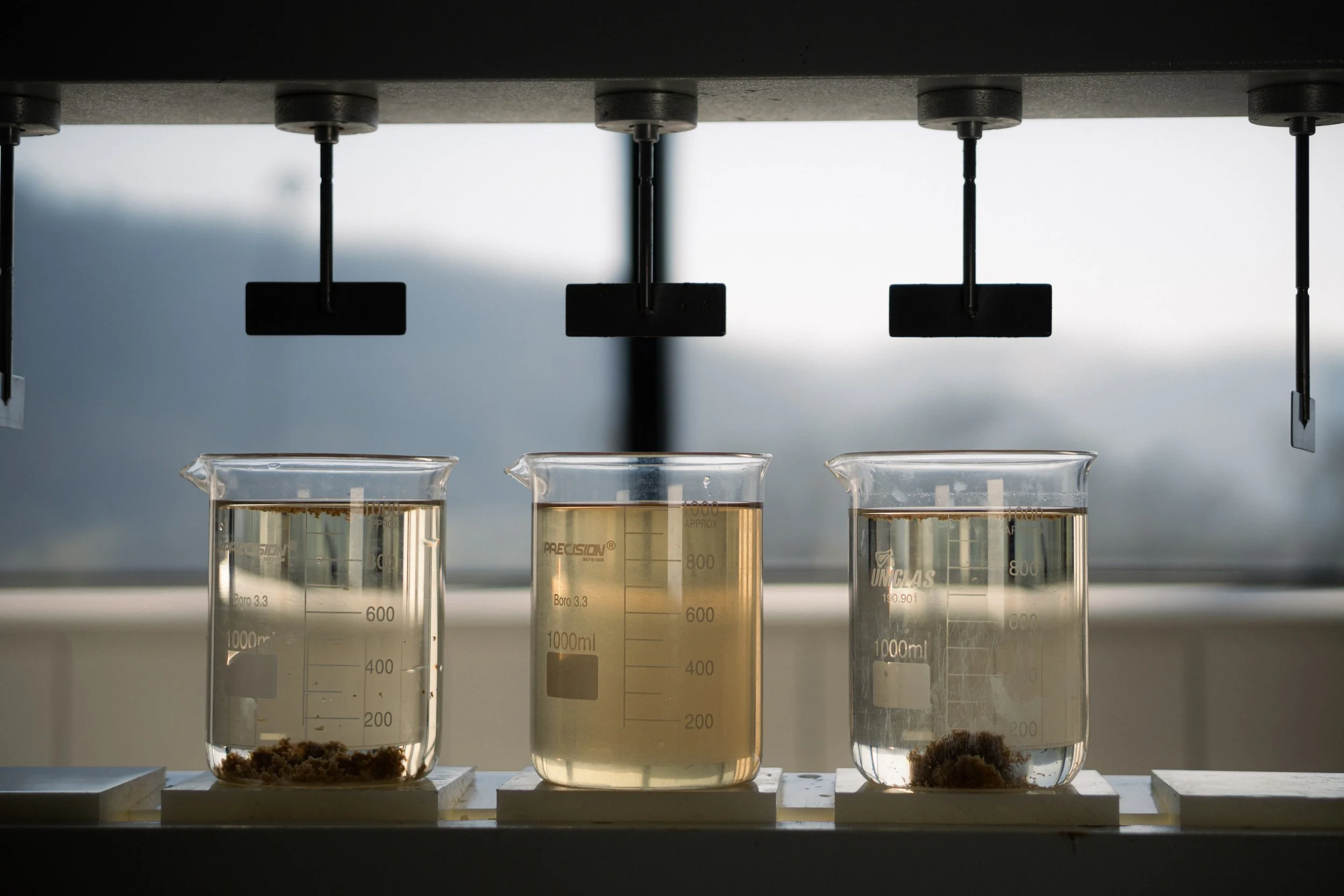 Jar test com três béqueres de efluente em agitação no laboratório