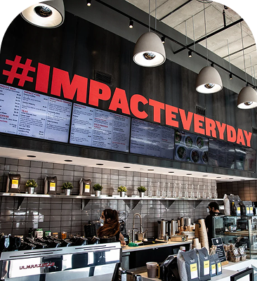 Impact Kitchen café interior with a modern service counter, digital menu boards and bold red signage.