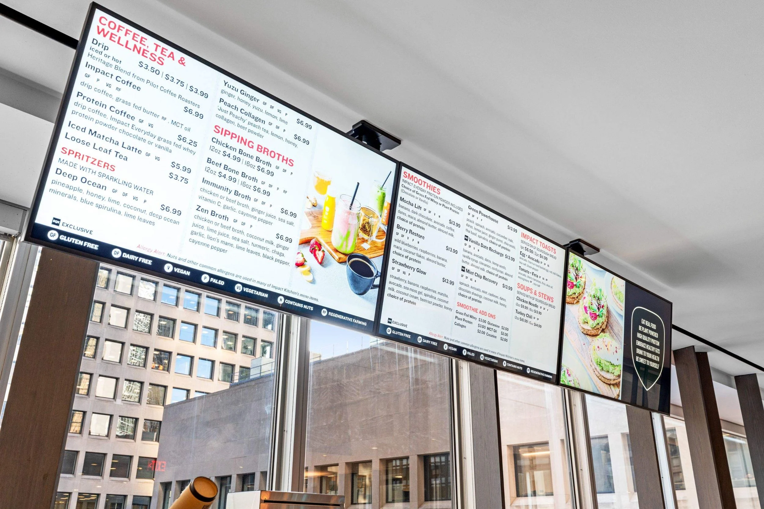 Digital café menu boards displaying coffee, smoothies, soups, and food options above the service counter.