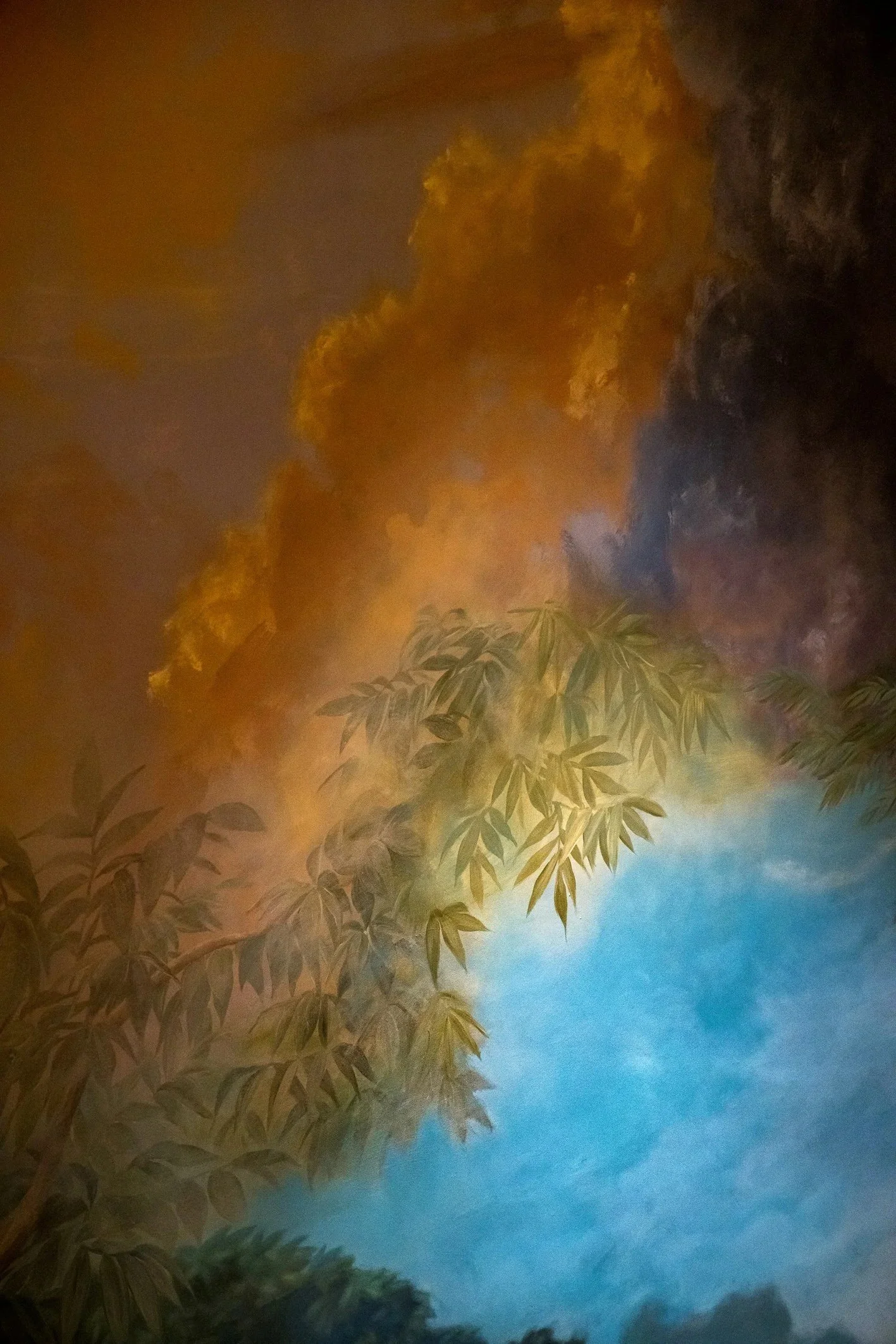 Atmospheric hand-painted mural depicting dramatic clouds, blue sky, and leafy tree branches, creating a serene nature-inspired backdrop with rich, painterly detail.