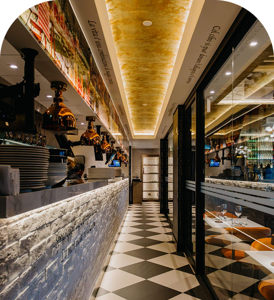Elegant restaurant interior with a brick bar, black-and-white tiled floor and warm illuminated ceiling.
