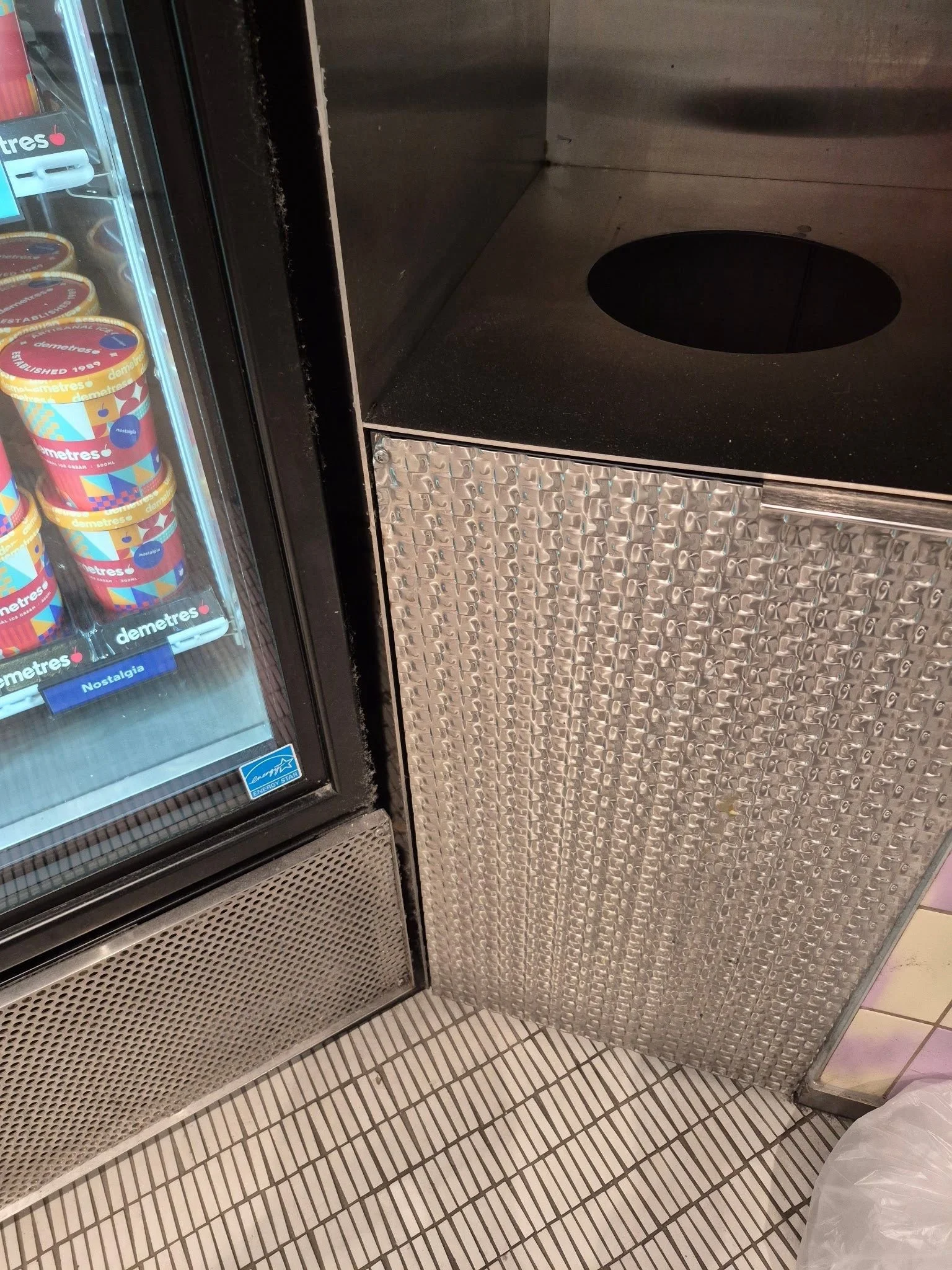 Textured stainless steel cabinet beside a refrigerated ice cream display at Scooped by Demetres.