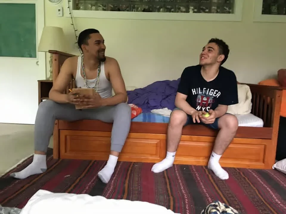 Two participants talking on a couch beside a sunny window.