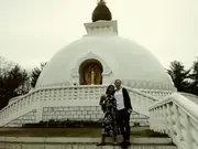 A person standing in front of a white peace pagoda.