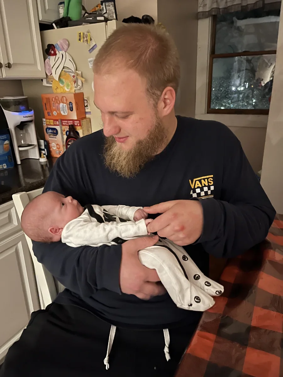 An adult holding a newborn in a home.
