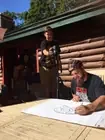 Participants drawing a large poster on a sunny deck.