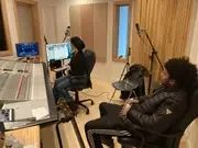 Participants seated beside the mixing desk in a recording studio.