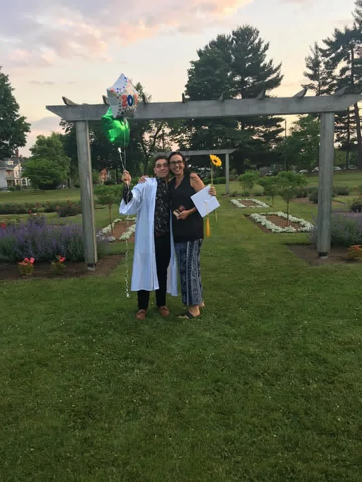 Two people posing together on a lawn after a graduation.