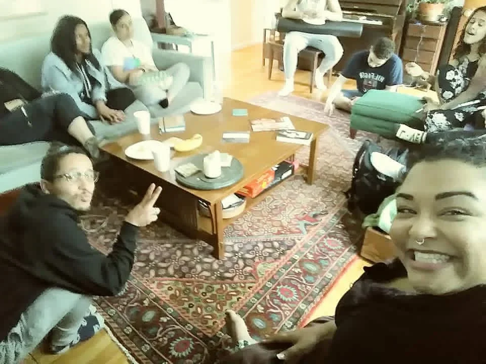 A group sharing refreshments around a living-room table.
