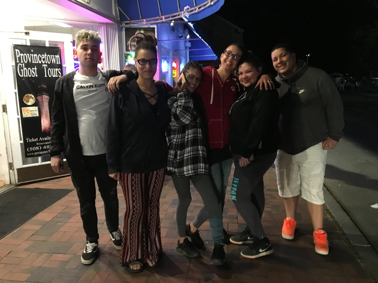 A group gathered outside a brightly lit venue at night.