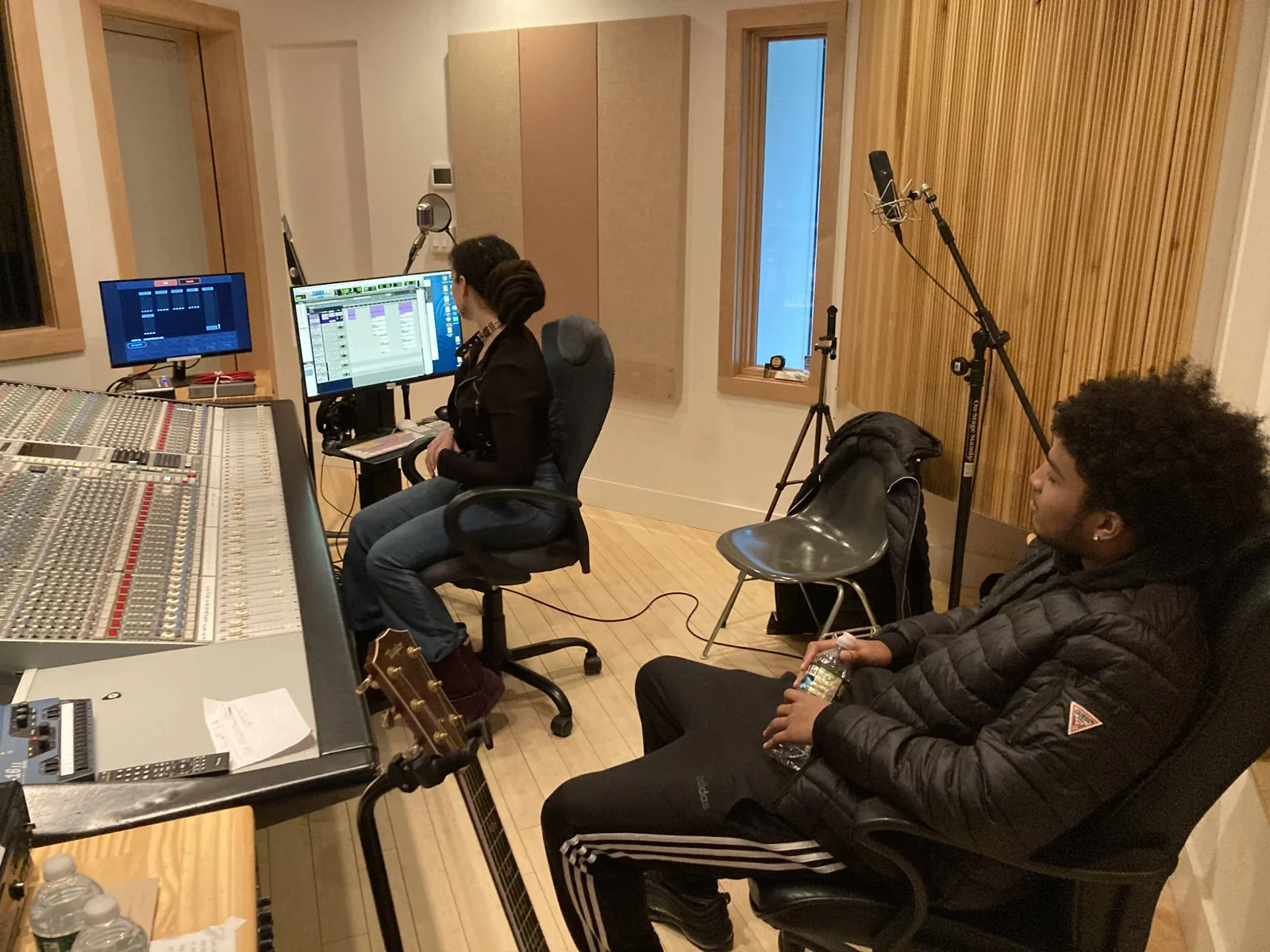 Participants seated beside the mixing desk in a recording studio.