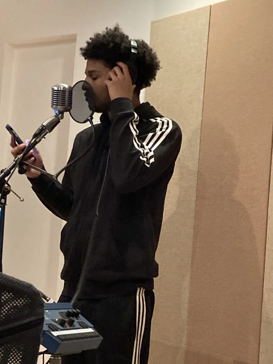 A participant standing at a microphone in a recording space.