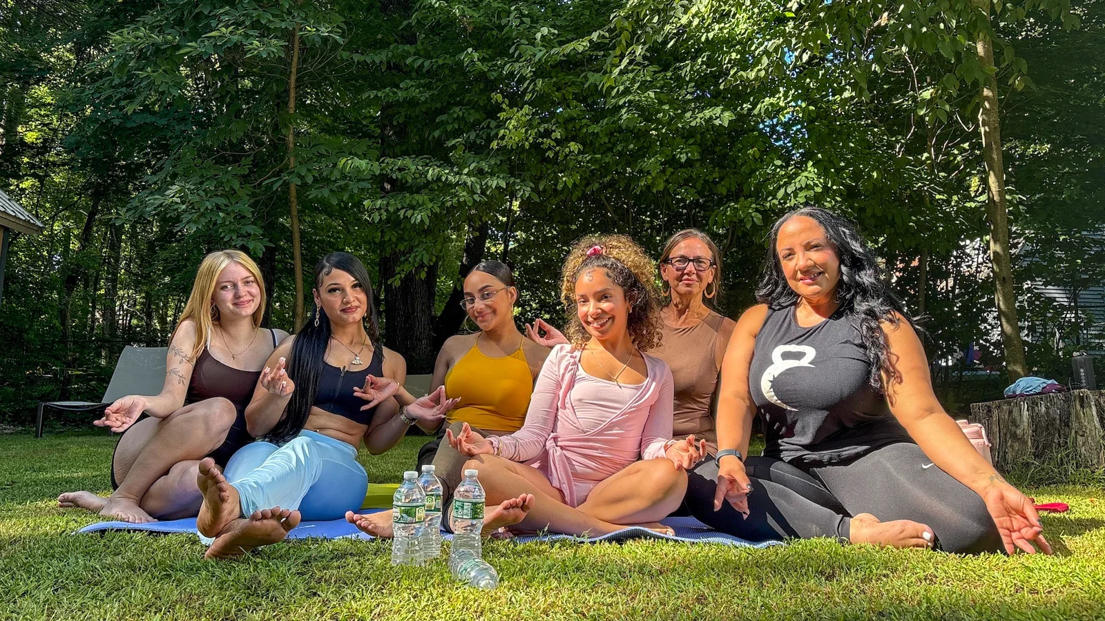 A group seated together on the grass beneath trees.