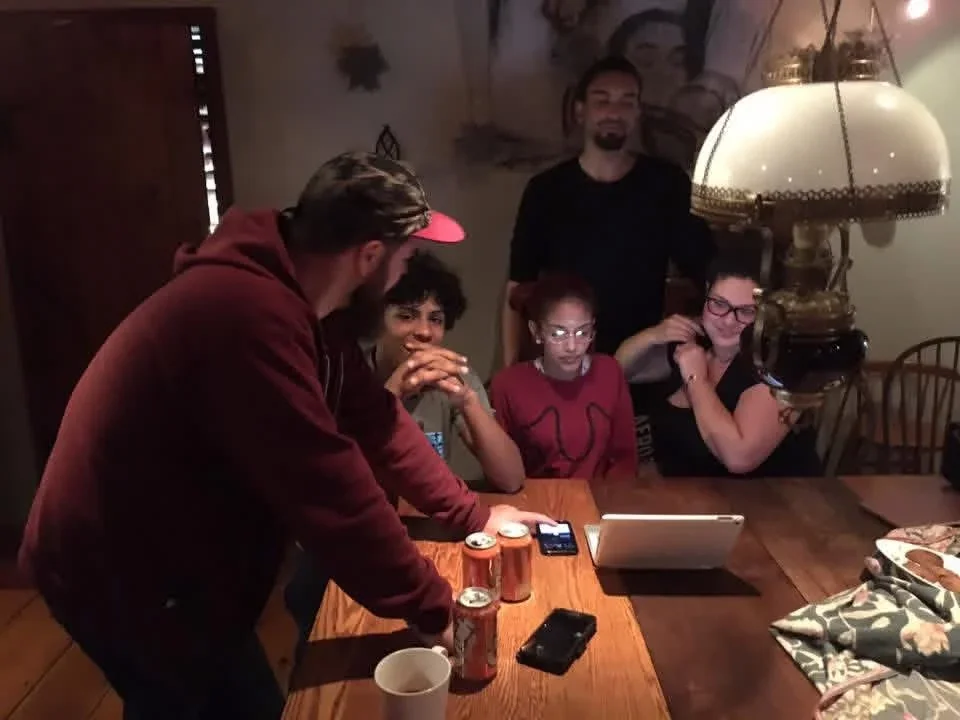 A group working together around a table in a wooden cabin.