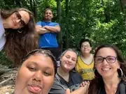 Friends taking a group selfie on a wooded trail.