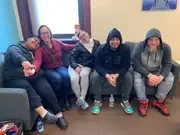 Five participants leaning together for a group photo on a couch.