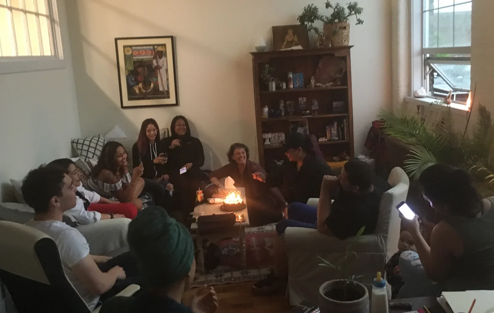 A group seated in a circle around a candlelit table.